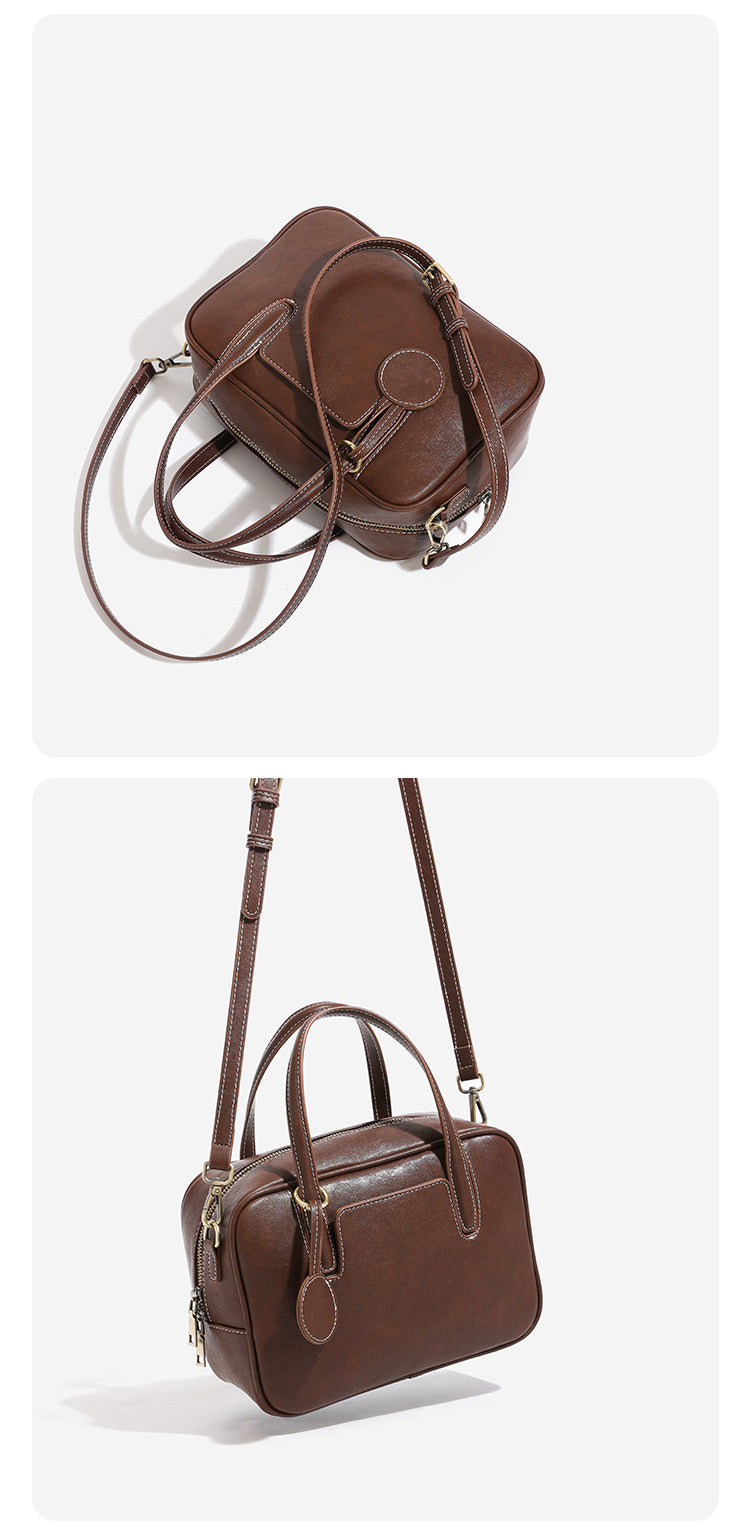 Structured boxy bowling-style tote bag in deep brown leather-look finish with dual top handles, front slip pocket, round