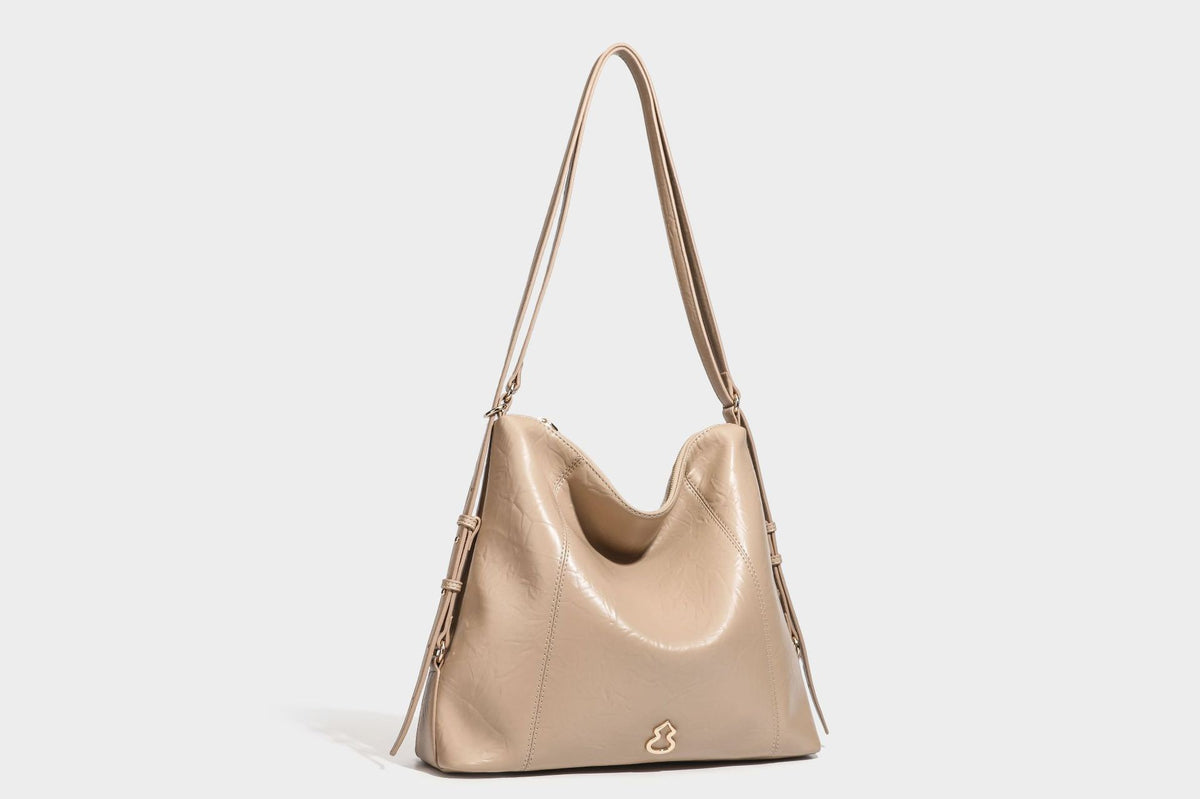 Große, lässig fallende Hobo-Schultertasche in glänzender, geknautschter Lederoptik mit goldfarbenen Beschlägen und langem, verstellbarem Riemen