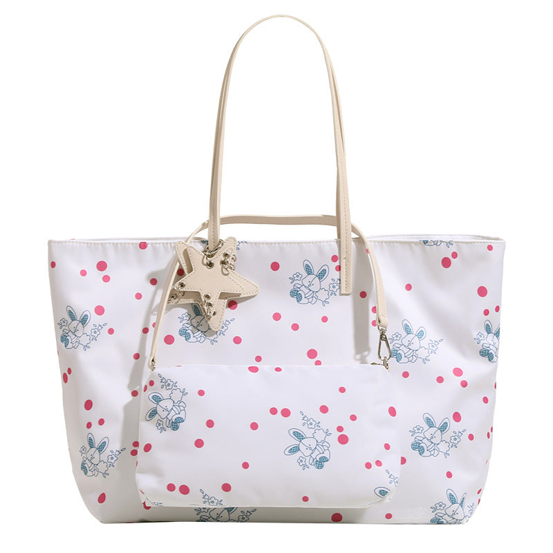 Large reversible floral print tote bag with slim shoulder straps, star charm hardware, and matching zip pouch, detail view 5