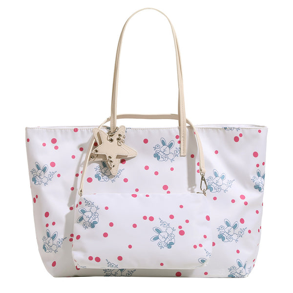 Large reversible floral print tote bag with slim shoulder straps, star charm hardware, and matching zip pouch, detail view 5