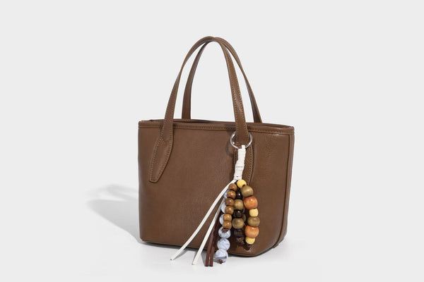Compact structured bucket tote bag with pebbled textured finish, dual top handles, silver-tone lock hardware, and detachable