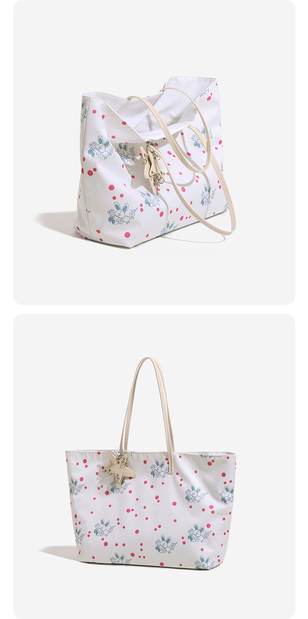 Large reversible floral print tote bag with slim shoulder straps, star charm hardware, and matching zip pouch, detail view 8