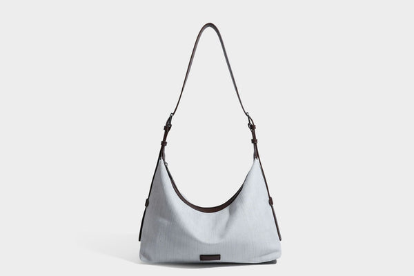 Slouchy olive green canvas hobo shoulder bag with black leather-look trim, zip-top closure, and adjustable strap, detail view