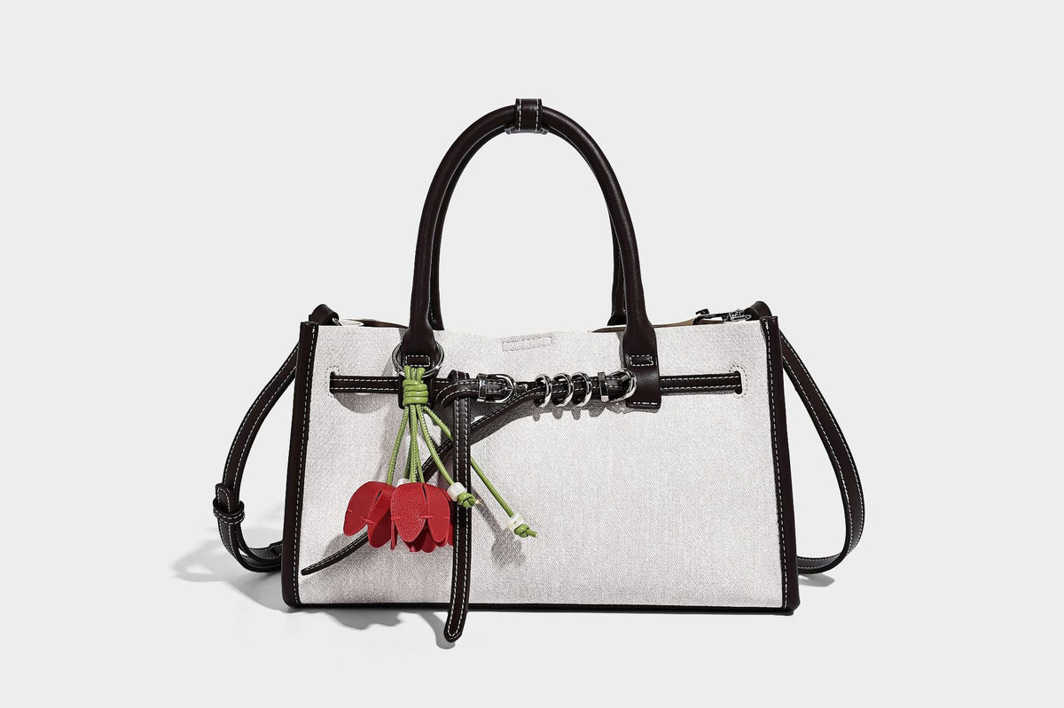 Structured rectangular tote satchel in denim-look fabric with dark trim, knotted front strap hardware, and detachable, detail