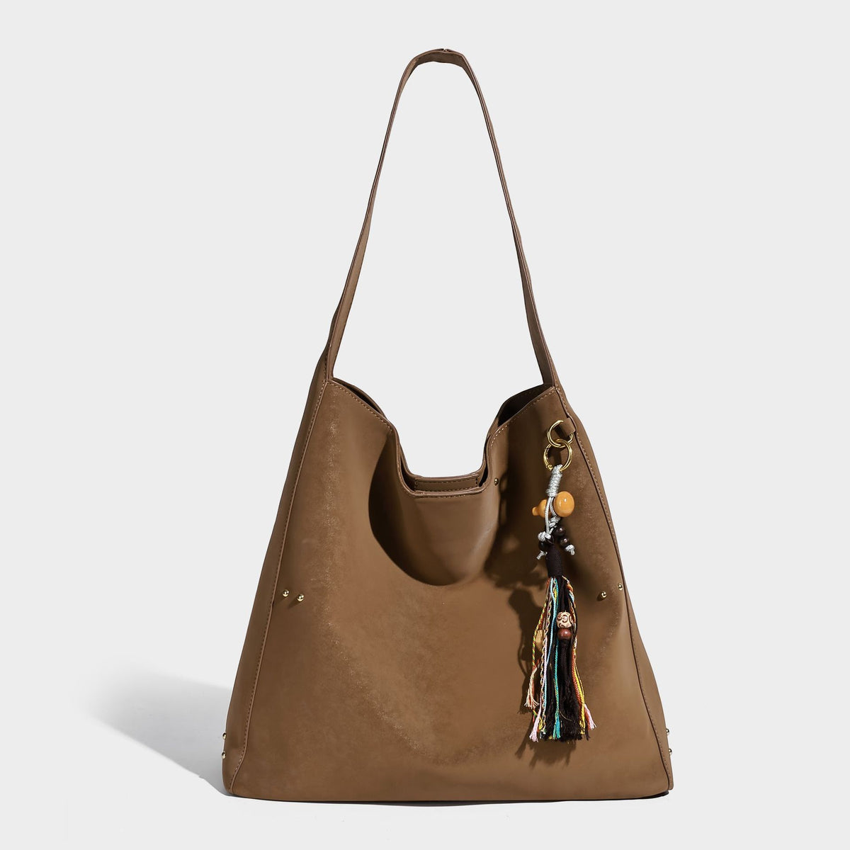 Oversized trapezoid tote bag with matte leather-look finish, gold-tone rivets, and long shoulder strap, detail view 3