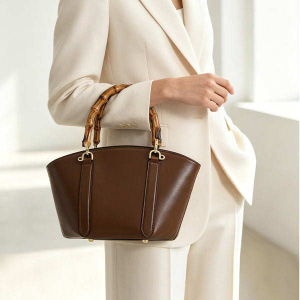 Structured trapezoid handbag with segmented bamboo top handle, smooth leather-look finish, gold-tone hardware, and vertical