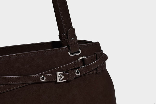 Structured trapezoid shoulder tote in dark brown matte suede-look finish with dual straps, wraparound belt bands