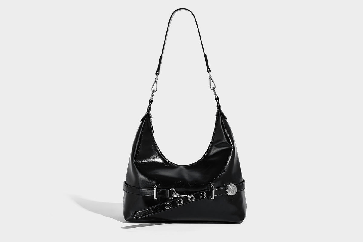 Glossy black slouchy hobo shoulder bag with silver-tone hardware, belt-style grommet strap at base, and long adjustable