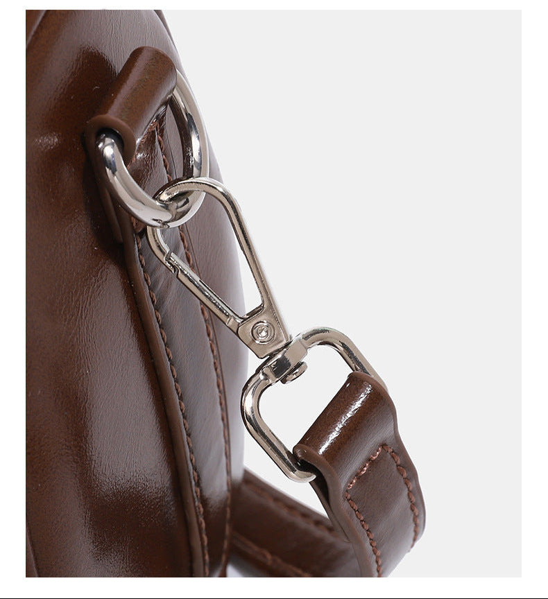 Kleine, formstabile Glanzledertasche mit zwei Henkeln, vorderer Klappentasche, herzförmigem Charm-Verschluss und silberfarbenem