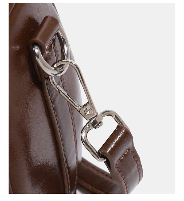 Kleine, formstabile Glanzledertasche mit zwei Henkeln, vorderer Klappentasche, herzförmigem Charm-Verschluss und silberfarbenem
