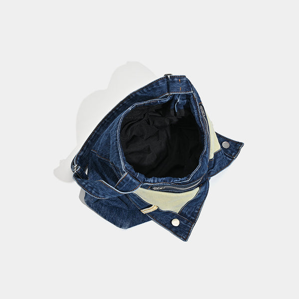 Schultertasche aus indigoblauem Denim mit hellen Kontrastpartien, sichtbarem Reißverschluss in Silberoptik, Druckknopfdetails und langem verstellbarem