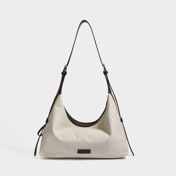 Cream canvas hobo shoulder bag with dark brown leather-look trim, zip-top closure, adjustable strap, and silver-tone