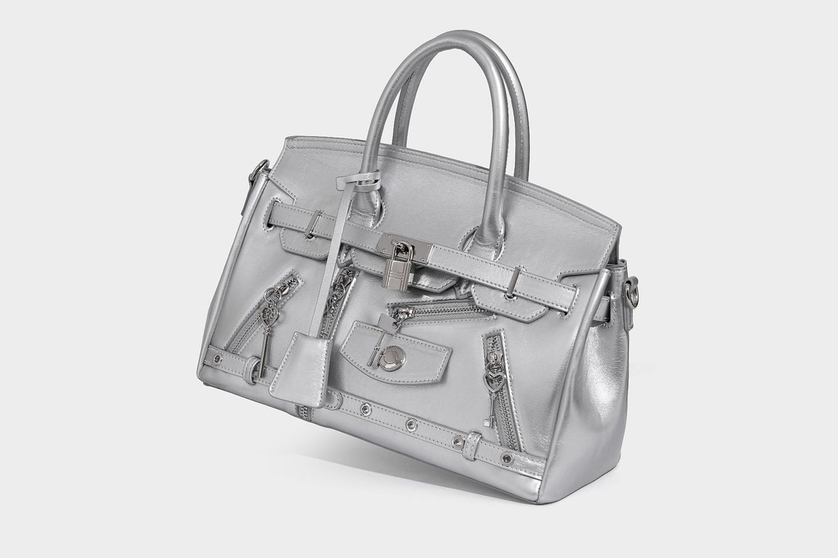 Structured black leather-look satchel bag with silver padlock hardware, front zip pockets, key charms, and top handles