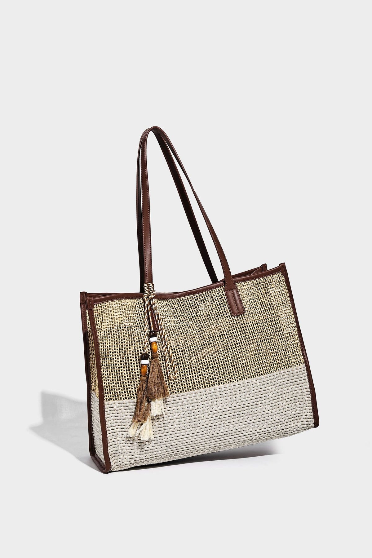 Große Tote-Bag aus grob geflochtenem Stroh in Beige und Creme mit dunkelbraunen Details in Lederoptik, langen Schulterriemen und einem mit Perlen verzierten