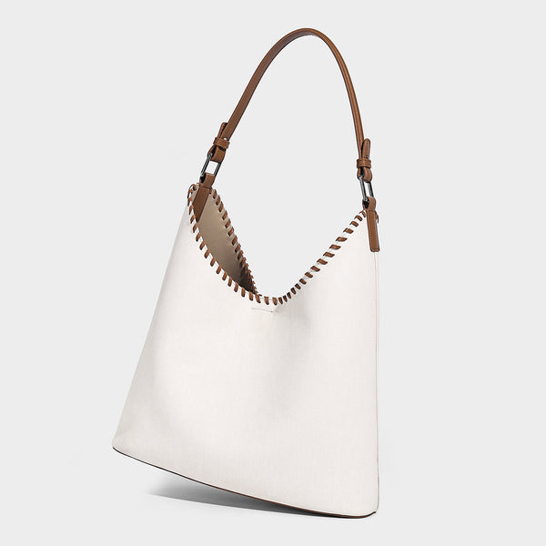 Denim-blue hobo tote with white leather-look shoulder strap, contrast whipstitch trim along curved open top, and silver-tone