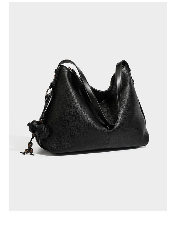 Slouchy hobo shoulder bag with pebbled leather-look finish, zip-top closure, gold-tone hardware, and hanging bead charm