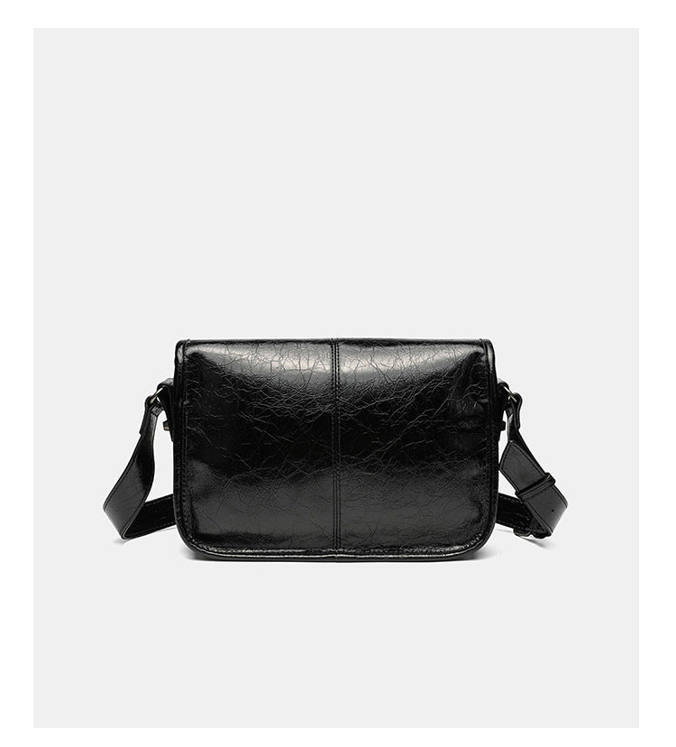 Small structured rectangular crossbody bag with crinkle leather-look finish, front zip pocket, gunmetal stud hardware, and