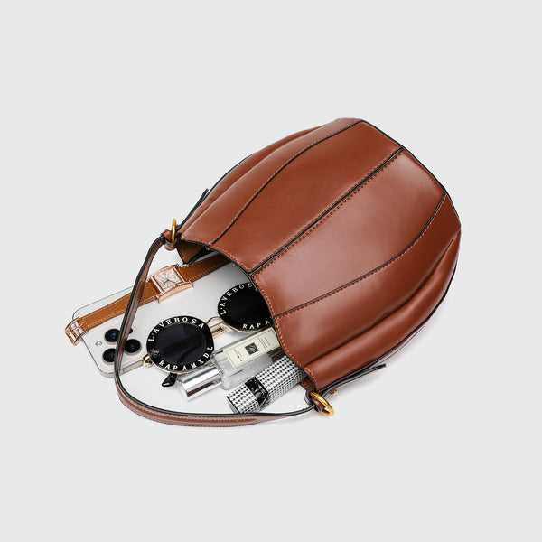Smooth leather-look paneled bucket bag in brown with wide woven shoulder strap, gold-tone ring hardware, and detachable zip