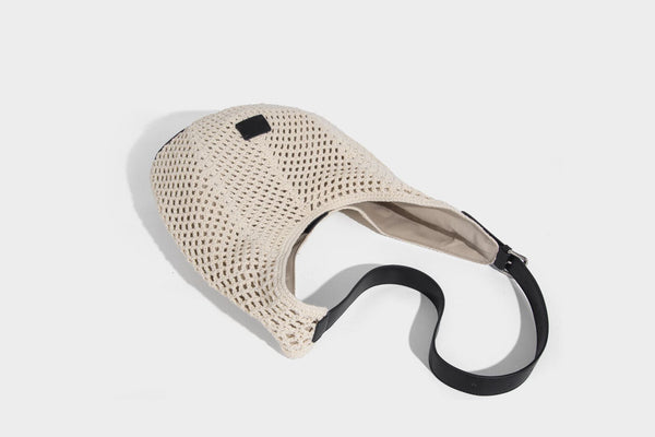 Cream openwork crochet hobo bag with black leather-look strap and trim patch accent, slouchy teardrop silhouette, detail view