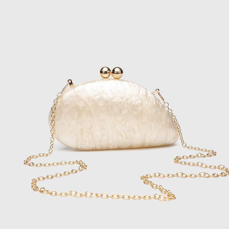 Ovale Hartschalen-Clutch mit marmorierter Perlmuttschimmer-Oberfläche, doppeltem Kugelverschluss in Goldoptik und Kettenriemen in Goldoptik, Detailansicht
