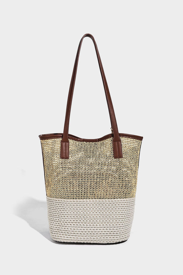 Woven straw-look tote bag in tan and cream with dark brown leather-look trim, long flat shoulder straps, and tassel bead