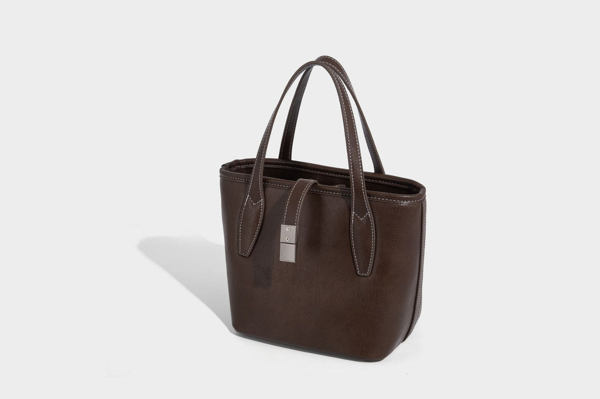 Compact structured bucket tote bag with pebbled textured finish, dual top handles, silver-tone lock hardware, and detachable
