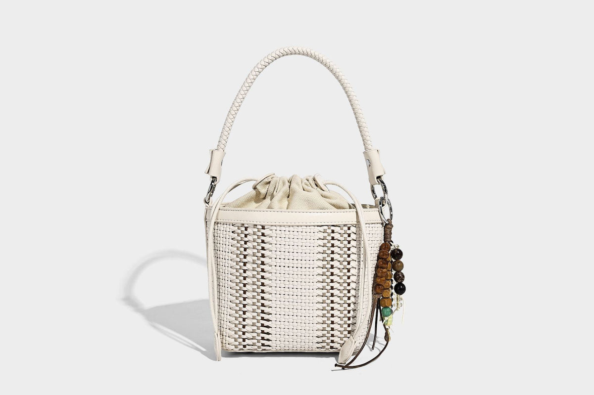 Small woven bucket bag with drawstring top, braided handle, detachable crossbody strap, and silver-tone ring hardware, detail