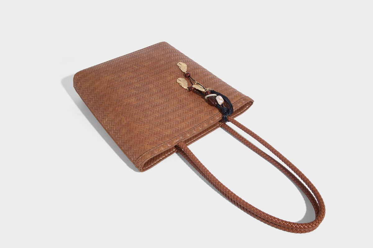 Structured woven herringbone tote bag with braided double shoulder handles in tan brown, shown with matching drawstring