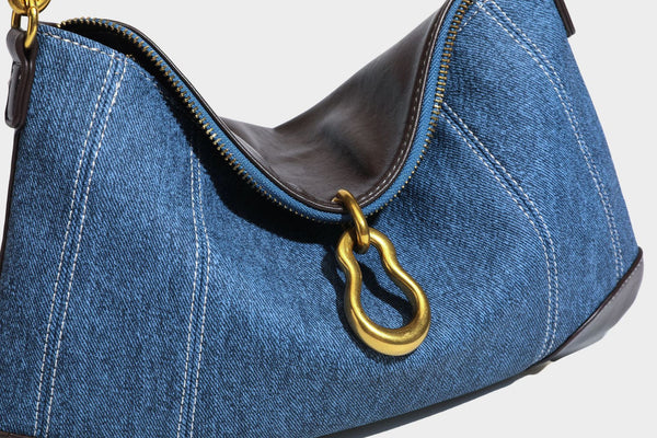 Slouchy denim shoulder bag with dark leather-look trim, gold-tone chain-link hardware, and top zipper closure, detail view 27