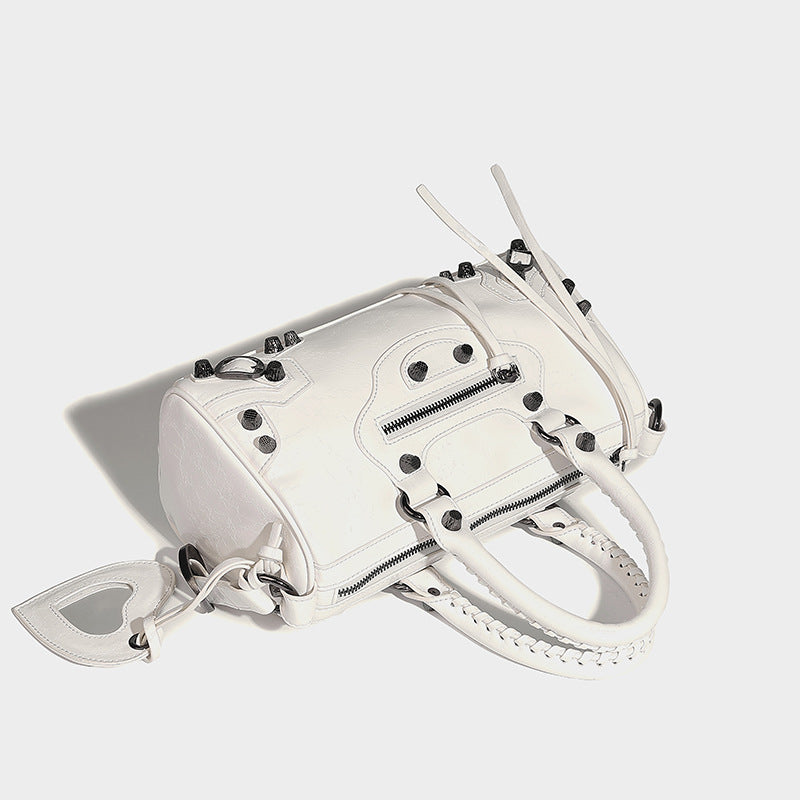Glossy studded mini satchel bag with braided top handles, front zip pocket, heart charm, and detachable crossbody strap