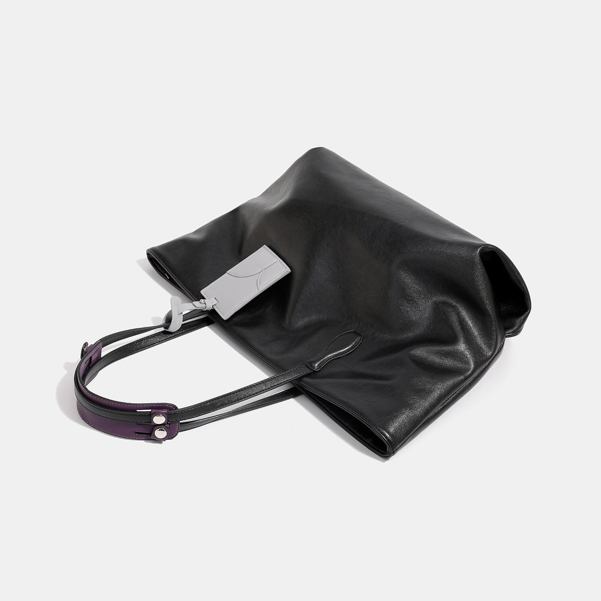 Large soft trapezoid tote bag with leather-look finish, dual shoulder straps, and gray hanging card tag, detail view 4