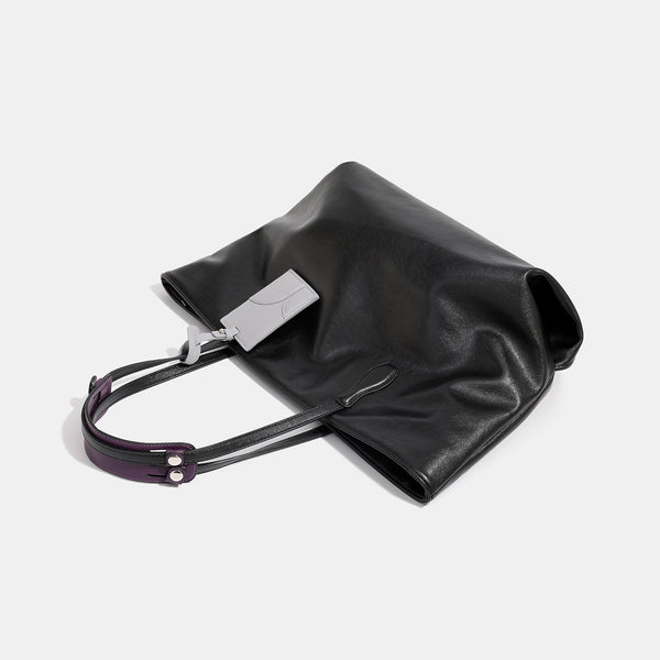 Large soft trapezoid tote bag with leather-look finish, dual shoulder straps, and gray hanging card tag, detail view 4