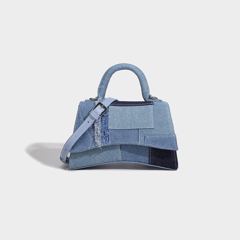 Structured patchwork denim trapezoid satchel bag with frayed panel trim, rounded top handle, and silver-tone hardware, front
