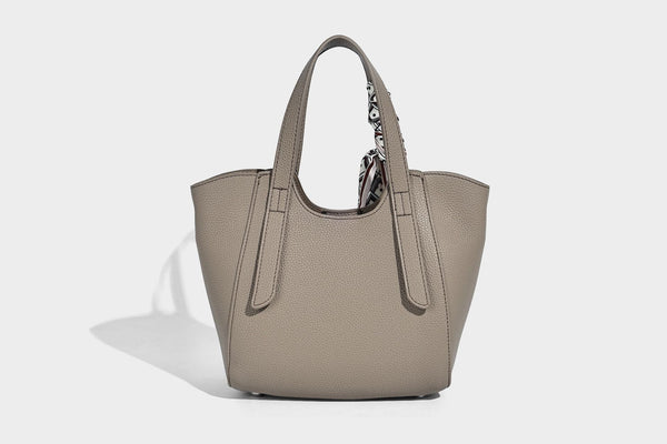 Structured pebbled leather-look tote bag with detachable scarf tie, dual top handles, and adjustable crossbody strap, detail