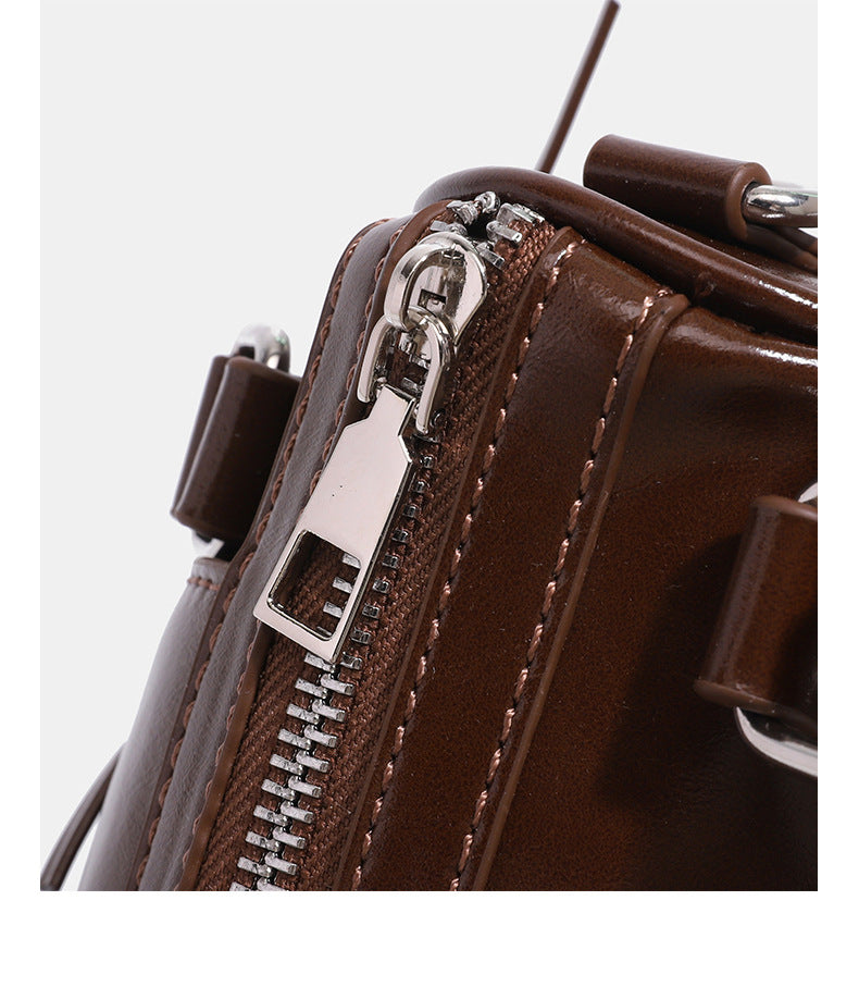 Kleine, formstabile Glanzledertasche mit zwei Henkeln, vorderer Klappentasche, herzförmigem Charm-Verschluss und silberfarbenem