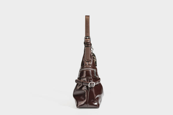 Glänzende dunkelbraune, lässig geschnittene Hobo-Schultertasche mit Riemendetail mit silberfarbenen Ösen, Reißverschlussfach auf der Vorderseite und Herz mit Leopardenmuster