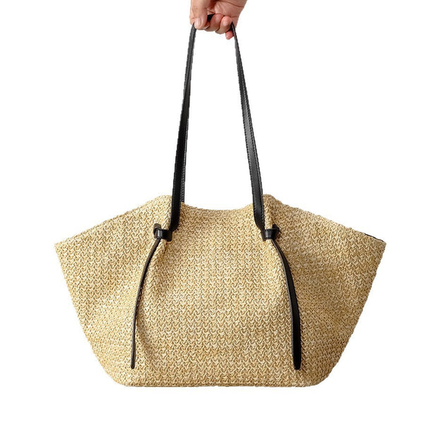 Großer geflochtener Strohs-Shopper mit schwarzen Schulterriemen aus Lederimitat und geknotetem Riemen-Detail, trapezförmiger Korpus in Natur-Tan