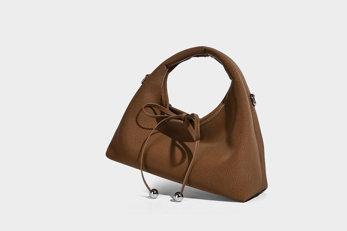 Pebbled matte trapezoid top-handle bag with drawstring bow closure, bead-tipped cords, silver-tone hardware, and detachable