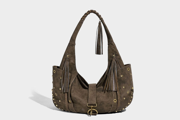 Slouchy crescent hobo bag in matte brown suede-like finish with gold-tone studs, grommets, braided top handle, tassel side
