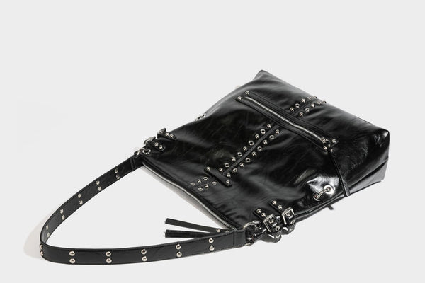 Black glossy leather-look slouchy shoulder bag with silver stud and eyelet hardware, top zip closure, front zip pocket, and