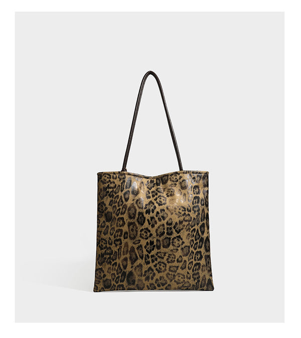 Large leopard print shoulder tote bag in tan and brown with slim dark straps and dangling beaded charm hardware, detail view