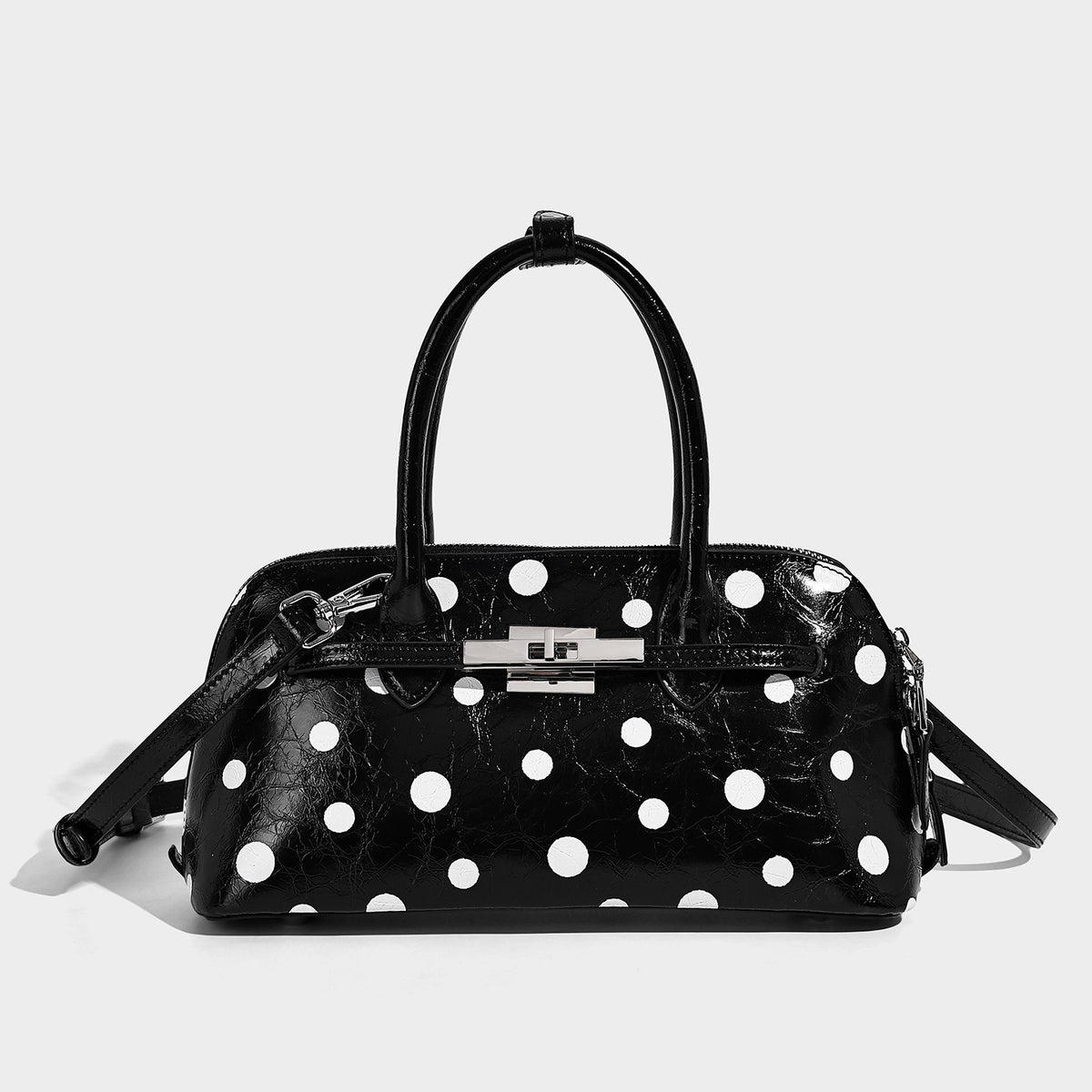 Structured polka-dot Boston bag with glossy crinkled finish, dual top handles, silver-tone turn-lock clasp, and detachable