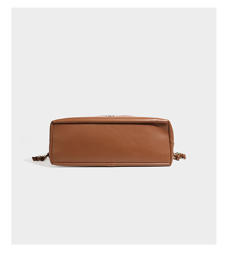 Slouchy ruched drawstring shoulder bag in smooth leather-look finish with gold-tone emblem and slim adjustable strap, detail
