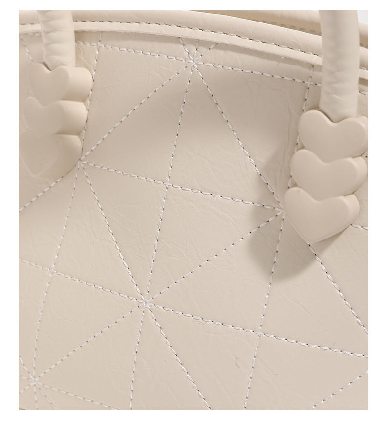 Quilted leather-look mini bucket tote bag with heart-shaped side accents, gold-tone hardware, fuzzy character charm, and