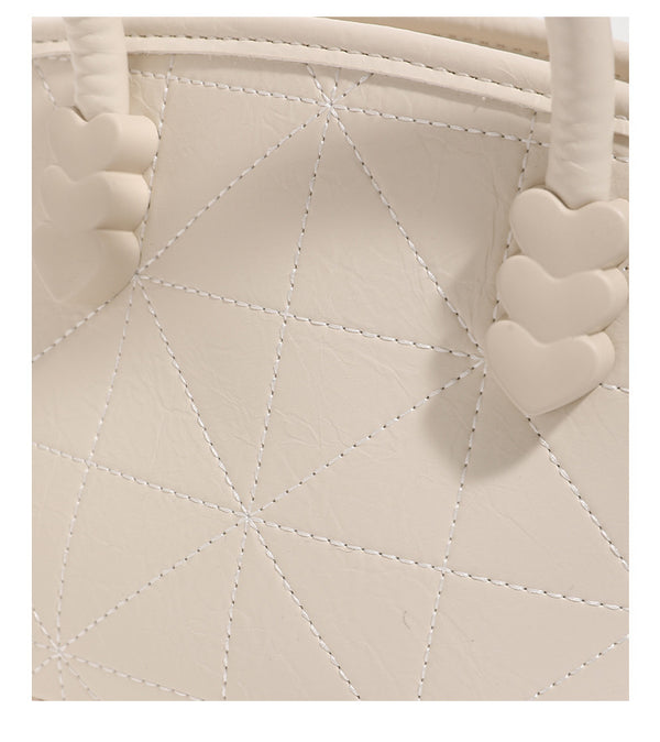 Quilted leather-look mini bucket tote bag with heart-shaped side accents, gold-tone hardware, fuzzy character charm, and