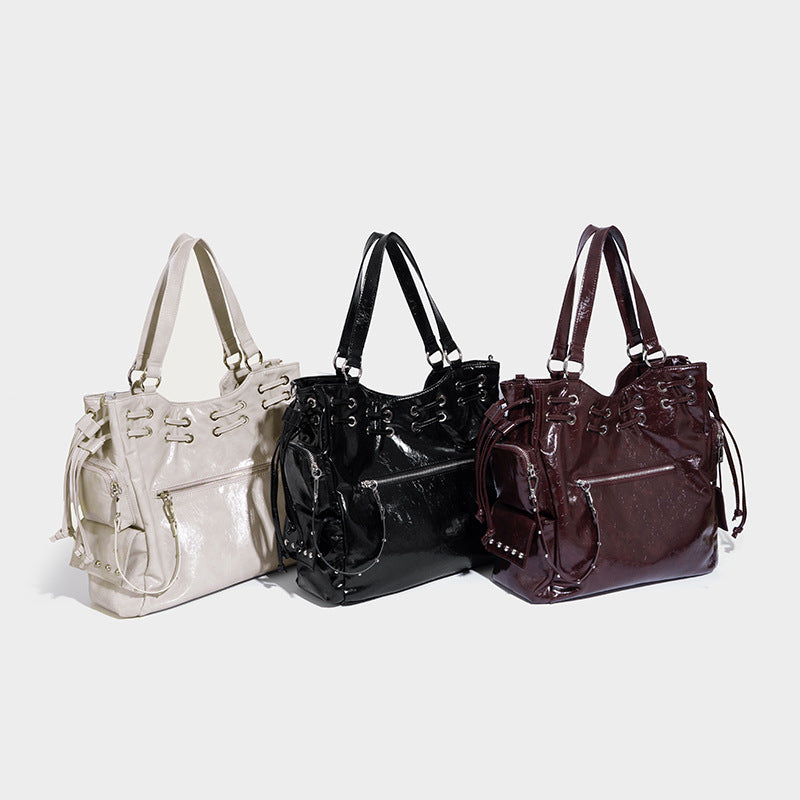 Glossy crinkled leather-look tote bag with silver grommet lace-up front detail, dual top handles, and detachable shoulder