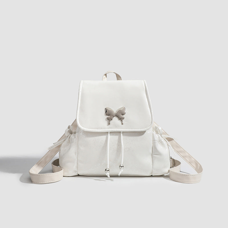 Compact white pearlescent flap backpack with silver-tone bow hardware and drawstring closure, detail view 6
