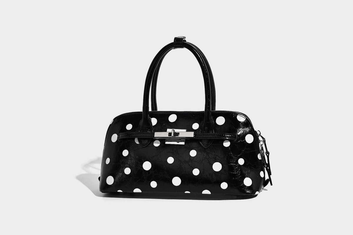 Glossy structured polka-dot satchel bag with dual top handles, silver turn-lock hardware, and detachable shoulder strap