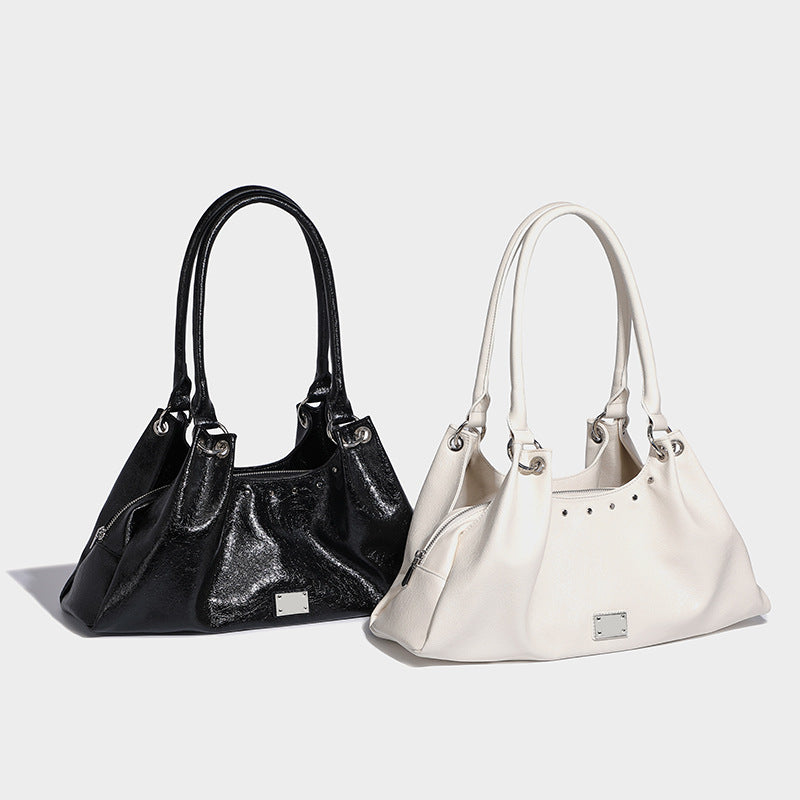 Slouchy trapezoid tote shoulder bag in glossy crinkled leather-look finish with twin looped handles, top zip closure, and