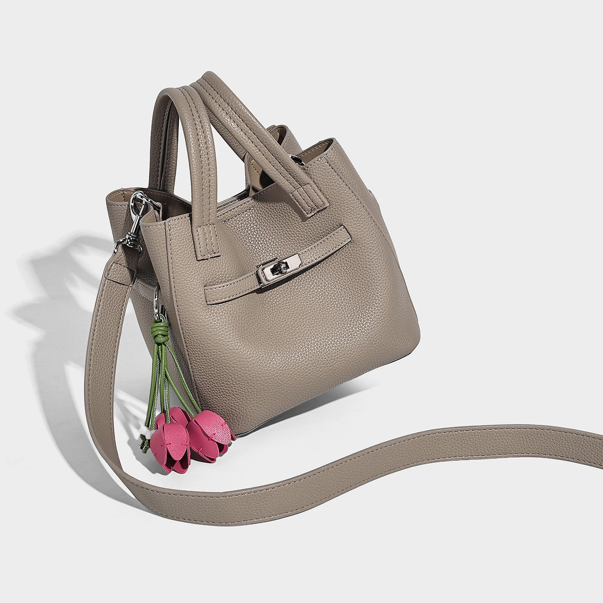 Small structured pebbled bucket tote bag with dual top handles, silver turn-lock front pocket, and detachable shoulder strap